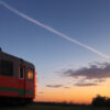 夕焼け空を背景に静かに停車するローカル列車のシルエット。 / A silhouette of a local train at rest against a vivid sunset sky.