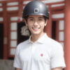 ヘルメットをかぶった若い男性が、和風の背景の中で笑顔を見せている。/ A young man wearing a helmet is smiling in front of a traditional Japanese-style background
