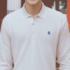白い長袖ポロシャツを着て笑顔を見せる若い男性 / A young man smiling in a white long-sleeve polo shirt