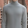グレーのタートルネックを着て笑顔を見せる若い男性 / A young man smiling in a gray turtleneck sweater