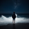夜の海岸で波を見つめる人物と星空 / Person standing on a nighttime beach watching waves under starlit sky