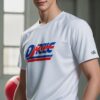 白いユニフォーム姿の青年が赤いドッジボールを抱えて体育館で微笑む A young man in a white uniform holding a red dodgeball and smiling in a gymnasium