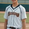 白いユニフォーム姿の青年がグローブを持ってソフトボール場に立つ A young man in a white uniform holding a glove, standing on a softball field