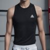 黒のノースリーブシャツと白いボクシングパンツを着た若い男性がリングで微笑んでいる。 / A young man wearing a black sleeveless shirt and white boxing shorts is smiling in the ring.
