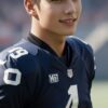 「40」番のアメフトユニフォームを着た若い男性がフィールドで横を向いて微笑んでいる。 / A young man wearing a number 40 American football uniform is smiling while looking sideways on the field.