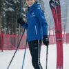 青と黒のスキーウェアを着た若い男性がスキー板を履いて雪山の斜面に立っている。 / A young man in blue and black ski wear is standing on a snowy slope wearing skis.
