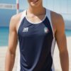 ビーチバレーコートで笑顔を見せる青年、濃紺のノースリーブユニフォーム姿 A young man smiling on a beach volleyball court, wearing a dark navy sleeveless uniform