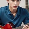 Young man in a blue polo shirt pressing complex guitar chords while playing （青いポロシャツの若い男性がギターで複雑なコードを押さえながら演奏している）