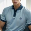 Young man in a light blue polo shirt turning a page with one hand while reading a book （薄い青色のポロシャツを着た若い男性が、本を読みながら片手でページをめくっている）