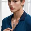Young man in a navy shirt delicately pinching a blue crystal necklace pendant with his fingers （ネイビーシャツの若い男性が青いクリスタルのネックレスを指で繊細につまんでいる）