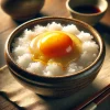 炊きたての白ご飯の上に新鮮な生卵がのった卵かけご飯 Raw egg placed on freshly steamed white rice in a traditional Japanese bowl